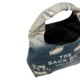 Bolso de hombro Marc Jacobs modelo The Sack Bag, confeccionado en denim azul con efecto desgastado y estampado del logo de la marca en blanco.