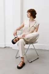 Sandalias planas de cuero sintético, con base negra y tiras anchas en forma de H en color caramelo o negro.