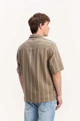 Camisa de manga corta oversize en tejido rústico, con diseño de rayas verticales celestes y blancas, cuello clásico y cierre frontal de botones.