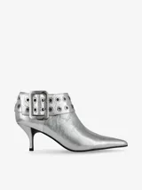 Botin de cuero plateado con acabado metalizado y efecto craquelado, con punta fina y taco fino. Presenta una tira decorativa en el tobillo con ojales metálicos y una hebilla grande.