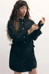 Vestido camisero negro con sobrefalda integrada, botones de nácar y estampado con leve rugosidad.