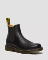 Botas Chelsea Dr. Martens modelo 2976 YS, confeccionadas en cuero liso negro. Presentan paneles laterales elásticos, costuras amarillas características en la suela y la clásica tira trasera con logo.