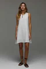 Vestido corto de lino blanco, sin mangas, con cuello redondo y diseño holgado.