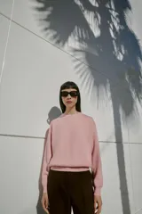 Jersey de punto liso con cuello redondo y manga larga, con detalle de costura en forma de V en el cuello.
