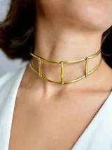 Gargantilla rígida de diseño minimalista, elaborada artesanalmente en bronce, con estructura de doble aro unida por barras verticales.