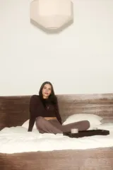Top de yoga cropped de manga larga, confeccionado en punto modal suave, color marrón. Cuenta con un escote en V pronunciado y una tira frontal para anudar.