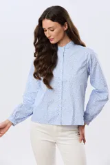 Camisa de algodón celeste con estampado floral pequeño, cuello mao, mangas largas con puños fruncidos y cierre frontal de botones.