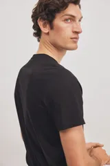 Remera negra de corte ajustado en punto suave de algodón pima, con cuello redondo ribeteado acanalado fino y bajo recto.