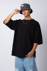 Remera de corte oversize, color negro, con cuello redondo y mangas cortas amplias.