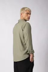 Camisa de manga larga con cuello clásico y cierre frontal de botones. Presenta un calce relajado y una textura liviana.