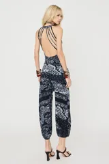Pantalón estilo balloon de color negro con estampado de estilo bandana con motivos florales y mariposas en blanco. Presenta tiro medio y puños elásticos en los tobillos.
