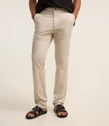 Pantalón slim color tostado, confeccionado en sarga, con cierre de botón y cremallera, y bolsillos tipo cuchillo.