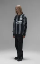 Sweater de punto con diseño a rayas verticales en negro y gris, cuello redondo y mangas largas. Presenta un estampado gráfico frontal con estilo deportivo retro que incluye el texto 'Ravers' y el número '90'. Cuenta con terminaciones en punto rib en cuello, puños y ruedo.