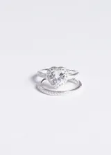 Set de dos anillos de plata 925, uno con dije central en forma de corazón con zirconia blanca y otro tipo alianza con zirconias engastadas en medio sin fin.