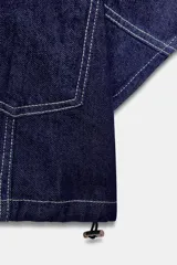 Camisa corta de denim de manga corta, con cuello solapa, escote en V y bolsillos delanteros de plastrón. Cuenta con costuras en contraste y cierre frontal con botones metálicos.
