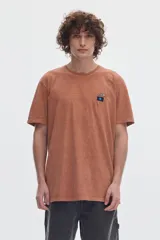 Remera marrón con efecto lavado y estampa pequeña en el pecho, de corte holgado y mangas cortas.