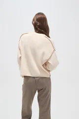 Sweater de algodón color natural, de corte holgado y cuello redondo. Presenta detalles de costuras decorativas con bordado en los hombros y puños acanalados.