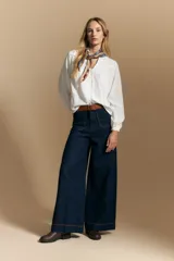 Camisa de manga larga color blanco, con cuello mao y escote en V. Presenta frunces en el canesú, cierre frontal con botones y mangas amplias con puños abotonados.