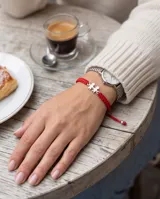 Pulsera de hilo rojo tejida en macramé con dijes de plata 925 en forma de nena y nene, con terminaciones de esferas de plata.