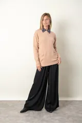 Buzo color beige con detalle de trenzado y distintos puntos en el frente. Tiene cuello redondo y dos bolsillos delanteros.