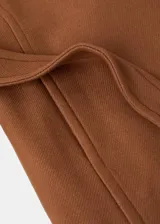 Abrigo largo de lana virgen en color marrón, con cuello solapa grande, cierre frontal y cinturón ajustable del mismo tejido. Presenta una silueta recta y bolsillos laterales.