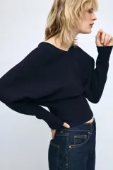 Jersey de punto color mostaza con escote en pico y manga larga con puños ajustados.
