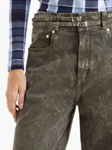 Pantalón wide leg de denim con lavado efecto gastado en tono verde oliva. Presenta cinco bolsillos, cierre frontal con botón y un cinturón integrado del mismo tejido con doble hebilla metálica.