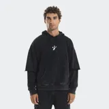 Hoodie oversize de color negro con efecto lavado, diseño de mangas superpuestas, bolsillo frontal tipo canguro y cordones ajustables en la capucha. Presenta un pequeño bordado en el centro del pecho.