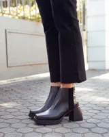 Botinetas de cuero negro con plataforma y taco cuadrado. Presentan un diseño combinado con una textura tipo reptil en la parte posterior y cierre lateral.