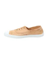 Zapatilla tipo sneaker de diseño ligero y fresco, confeccionada en algodón orgánico teñido a mano en tono arcilla. Presenta puntera reforzada de goma blanca, suela de caucho natural y ojales metálicos decorativos.