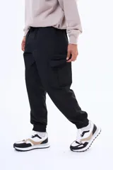 Pantalon cargo negro de corte holgado, con bolsillos laterales con solapa y puños elásticos en los tobillos. Cuenta con cintura elástica con cordón de ajuste.