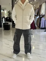 Chaleco puffer de cuerina beige, sin mangas, con cuello alto, cierre frontal y bolsillos laterales.
