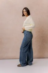 Jean wide leg de tiro medio-alto en denim azul medio con lavado desgastado. Presenta diseño de cinco bolsillos, cierre con botón y cremallera, y pierna amplia de caída recta.