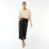 Falda larga de color negro con diseño cruzado y detalle de hebilla metálica dorada en la cintura. Presenta un corte midi con caída fluida y una abertura frontal.