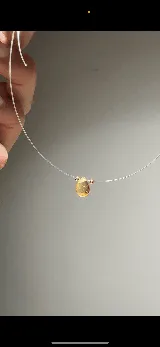 Gargantilla de tanza transparente con dije de piedra semipreciosa en forma de lágrima y separadores dorados.