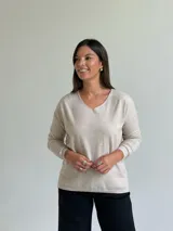 Sweater de punto fino en color beige, con escote en V y mangas largas con puños ajustados.