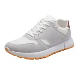 Zapatillas deportivas de mujer, estilo retro running, en tonos blanco y gris claro. Presentan una combinación de malla transpirable y paneles de gamuza sintética. La suela es gruesa y blanca, con una suela exterior de goma color caramelo. Detalle en el talón en color marrón.