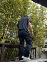 Pantalón negro de gabardina, corte ancho tipo carpenter, con costuras blancas contrastantes.