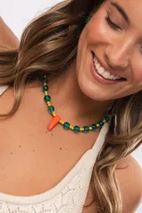 Collar corto de cuentas de cristal azules y verdes con un dije central en forma de cuerno de acrílico naranja.