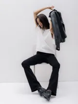 Pantalón de jean negro de tiro alto, corte ajustado en caderas y muslos, con pierna acampanada.