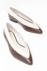 Chatitas de cuero con diseño bicolor, combinando tonos chocolate y off-white. Presentan una silueta de punta fina y un taco bajo de bloque.