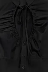 Top de popelín negro de manga corta abullonada, con cuello mao, escote en pico con lazada y cierre frontal con botones.