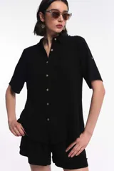 Camisa de manga corta color negro, de corte fluido, con cierre frontal de botones y cuello camisero.