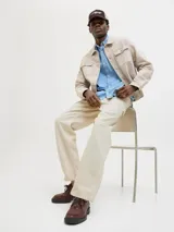 Pantalón jean color crema, corte amplio, con tiro alto, cinco bolsillos y cierre con botones.