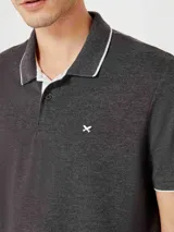 Chomba de manga corta color negro con cuello y tapeta interior en color gris claro. Presenta un pequeño bordado en el pecho y detalles de ribete en gris en el cuello y las mangas.