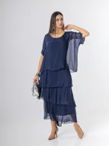 Vestido largo azul marino de seda italiana, con diseño de volados escalonados en la falda y una sobrecapa superior con mangas cortas amplias.