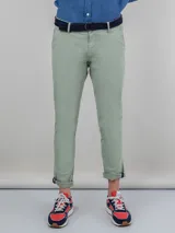 Pantalón chino verde claro confeccionado en tejido gabardina con 77% algodón, 20% de algodón reciclado y 3% elastano. Corte Slim Fit. Tiene bolsillos delanteros y en los traseros.