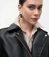 Campera estilo biker de poliuretano, con cierre frontal asimétrico, cuello con solapas y cremalleras en los puños. Presenta un diseño entallado con acabado liso.
