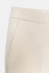 Pantalón de vestir color beige claro, tiro medio, con corte flare (campana) en el bajo. Presenta bolsillos laterales y falsos bolsillos de vivo en la espalda.