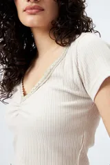 Remera blanca de punto acanalado con escote en V fruncido y puntilla en el borde.